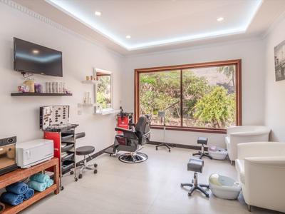 Moderner, heller Raum mit großen Fenstern, zwei Friseurstühlen, Fernseher und minimalistisch eingerichtet.