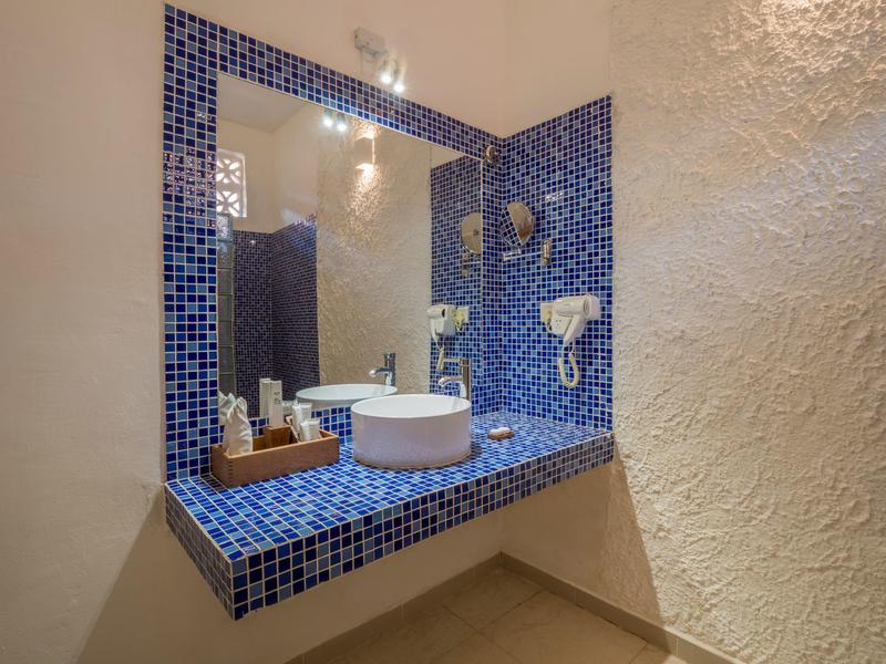 Moderner Badezimmerspiegel mit blau gefliester Ablage und rundem Waschbecken.