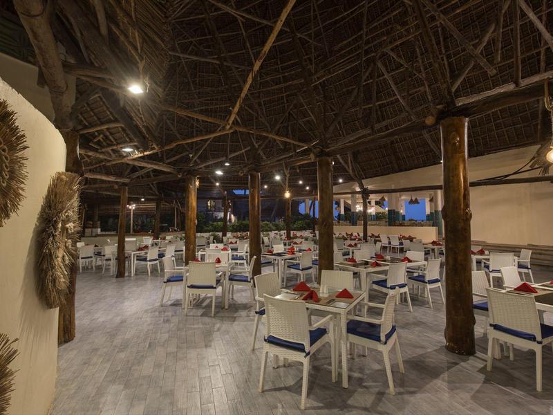 Großer, offener Speisesaal mit weißen Stühlen und Holzbalken unter einem hohen Dach.