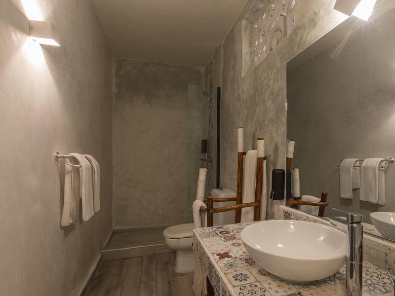 Modernes Badezimmer mit grauen Wänden, Waschbecken auf Mosaikplatten und großer Spiegelwand.