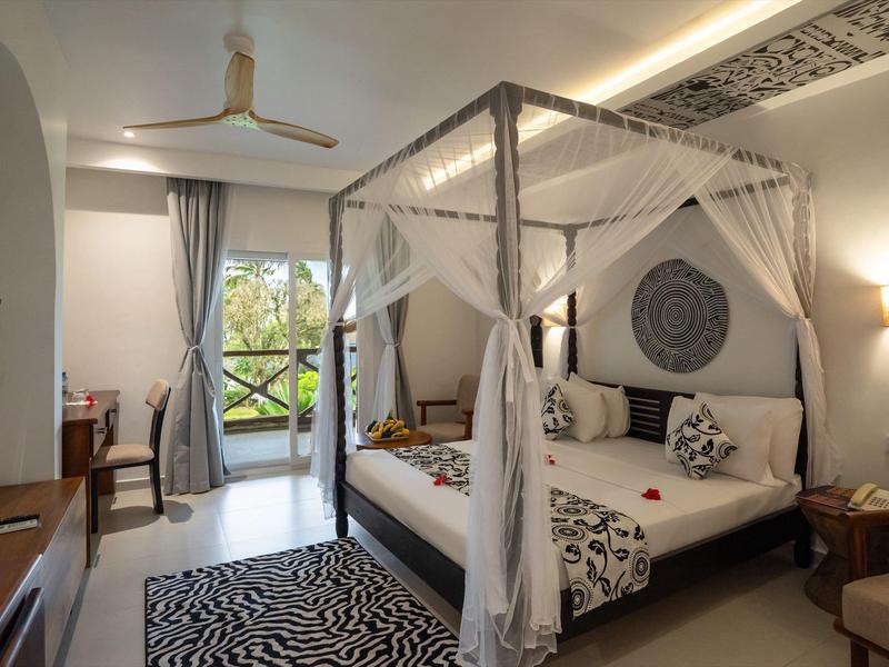 Elegantes Schlafzimmer mit Himmelbett, Zebra-Teppich und Balkon mit Blick ins Grüne.