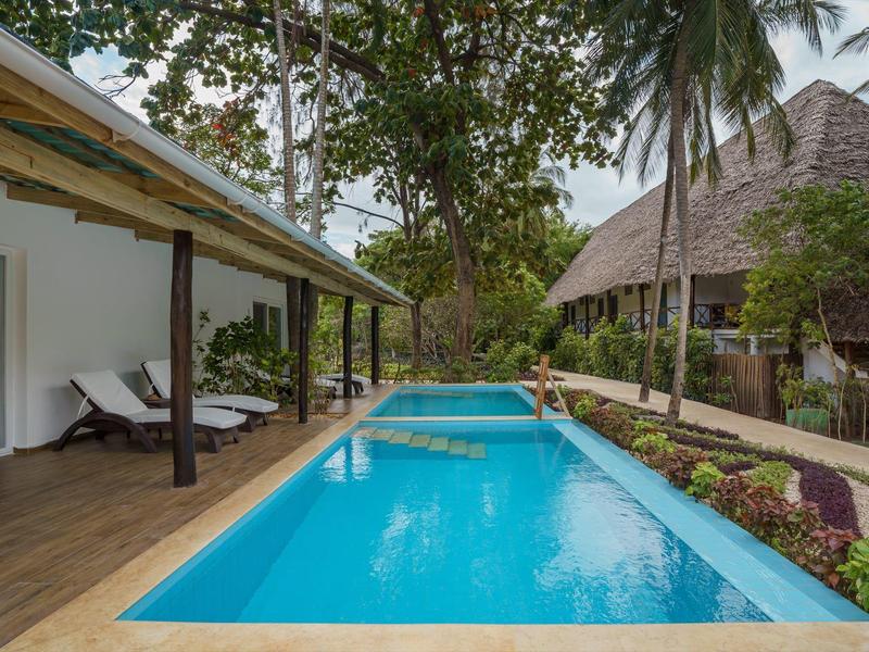 Modernes Hotel mit langem Pool, Liegestühlen und tropischen Pflanzen im Freien