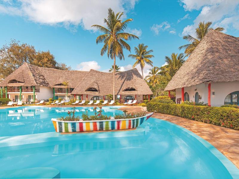 Modernes, helles Hotelzimmer mit Himmelbett, Sitzbank und offener Garderobe.