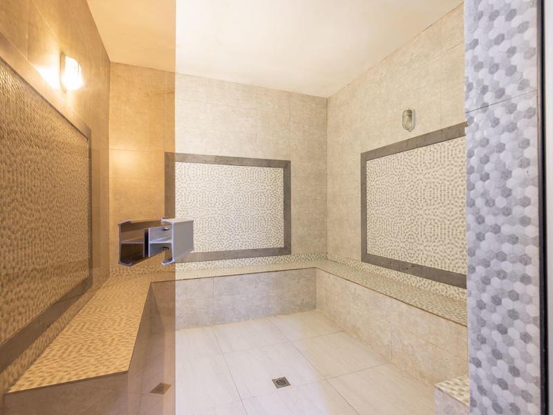 Helles Badezimmer mit eingemauertem Waschbecken und viel Spiegeln im modernen Stil.