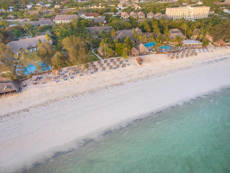 Strand mit Liegestühlen, Sonnenschirmen und Pools am Rande eines Resorts