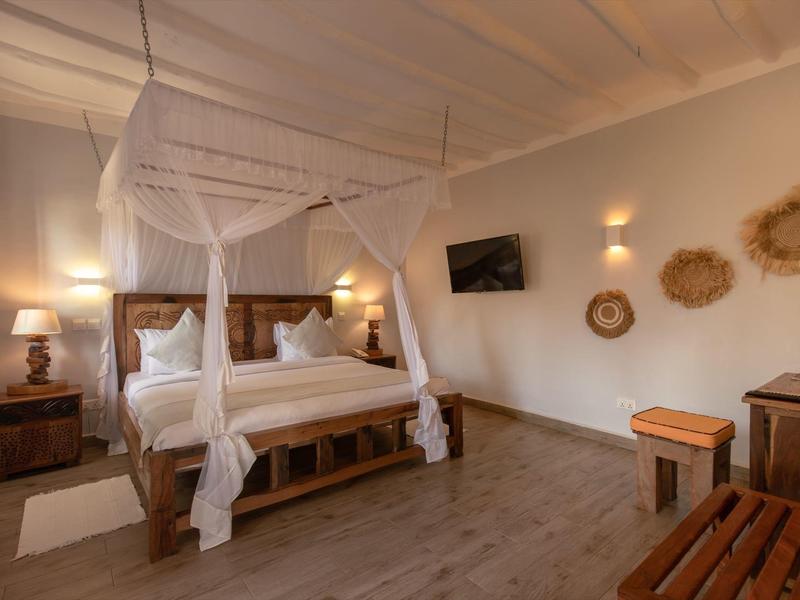 Elegantes Hotelzimmer mit Himmelbett, Holzmöbeln und warmem Licht.