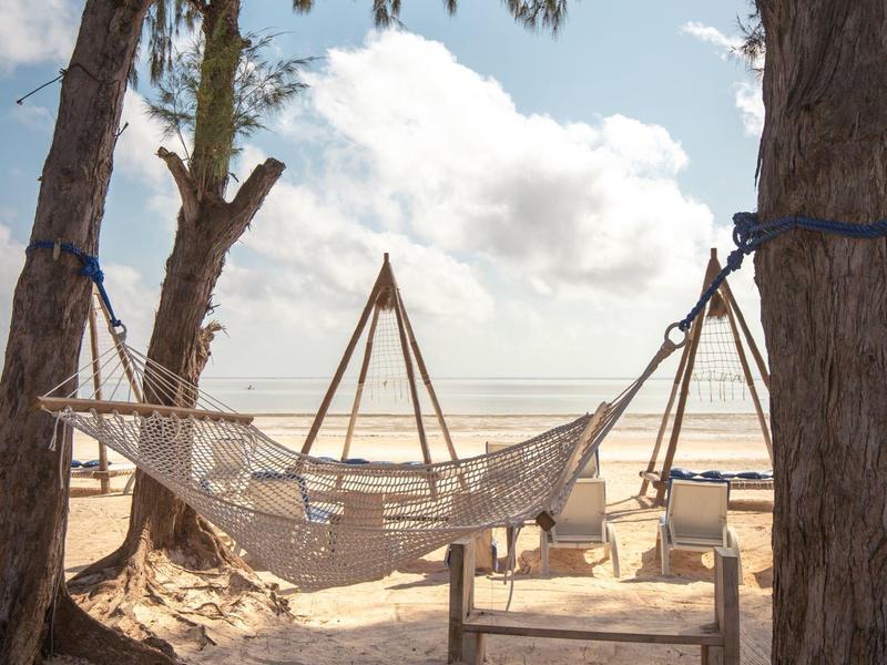 Hängematte zwischen Bäumen am Strand mit Blick auf das Meer und Sand.
