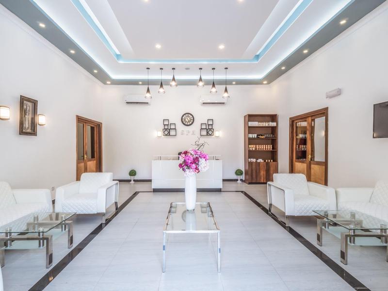 Helle, moderne Hotellobby mit weißen Sofas, Glas-Couchtischen und einer Blumendekoration.