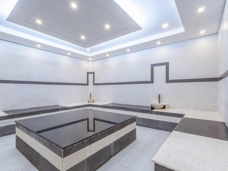 Moderner Wellnessbereich mit weiß-schwarzer Steinverkleidung und indirekter Beleuchtung.