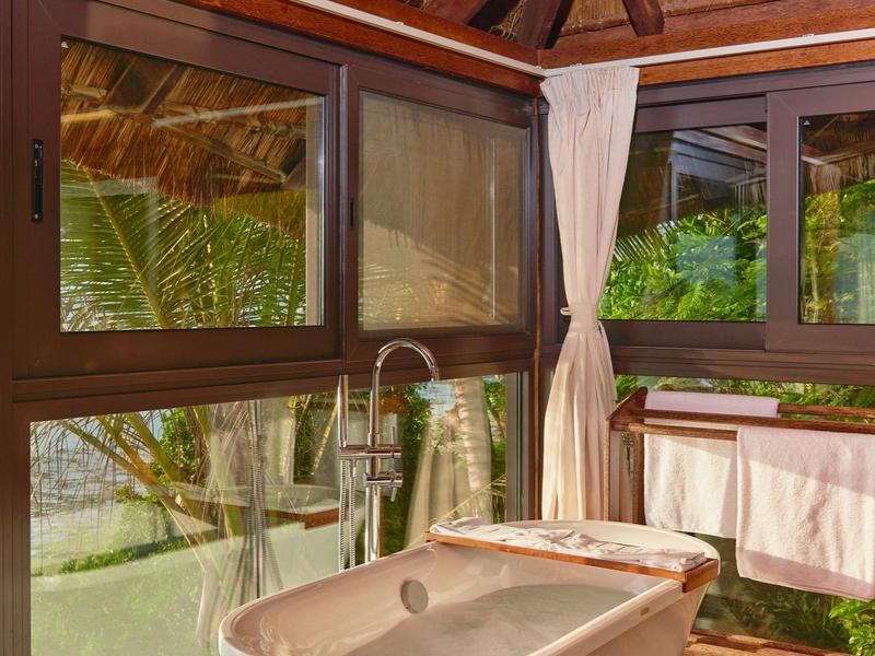 Freistehende Badewanne in holzintegriertem Badezimmer mit großen Fenstern und Blick ins Grüne.