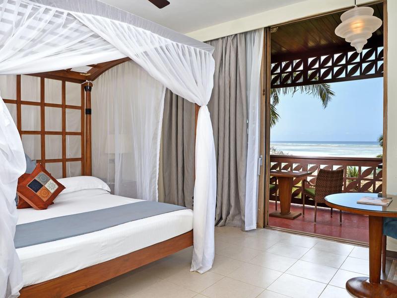 Helles, modernes Schlafzimmer mit Himmelbett und offenem Zugang zu Balkon mit Meerblick.