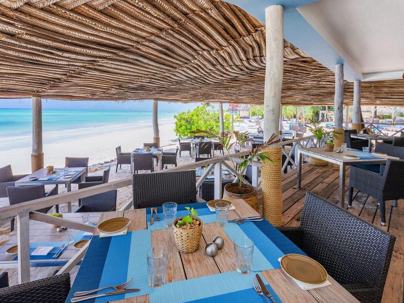 Großes Schlafzimmer mit Himmelbett, weißen Vorhängen und Zugang zu einem Balkon mit Palmenblick.