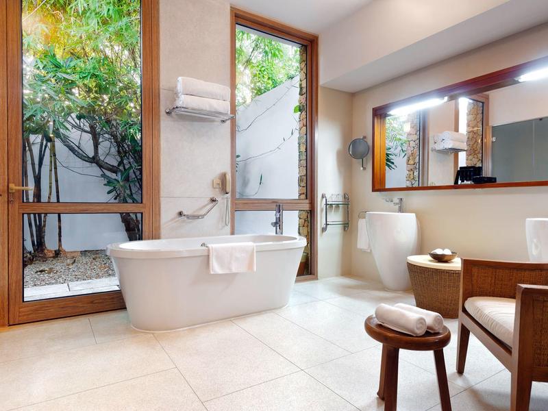 Helles Badezimmer mit freistehender Badewanne, großen Fenstern und Holzrahmen, modernem Design.