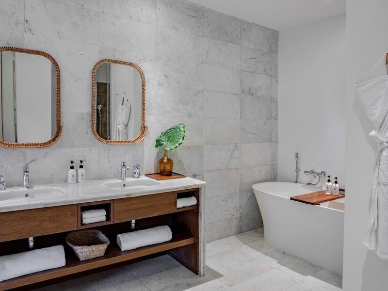 Modernes Badezimmer mit Doppelwaschbecken, freistehender Badewanne und hellem Marmorfliesen-Design.