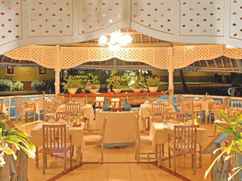 Eleganter Außenbereich eines Restaurants mit gedeckten Tischen und Holzmöbeln unter einer überdachten Terrasse.