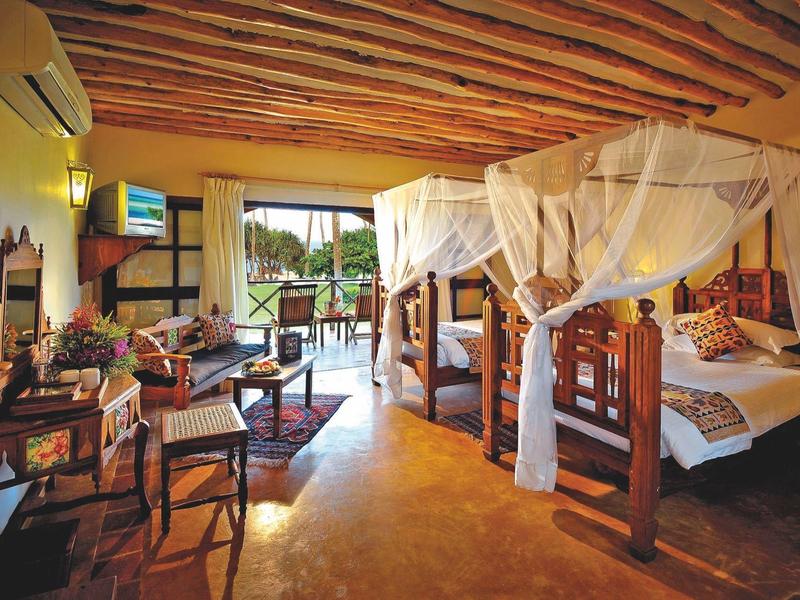 Geräumiges Hotelzimmer mit zwei Betten, Holzmöbeln und Moskitonetzen, Balkon mit Aussicht.