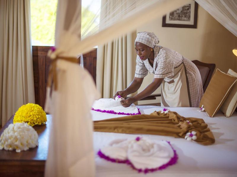 Hotelzimmer mit Bettenservice, der das Bett mit Blumen dekoriert.