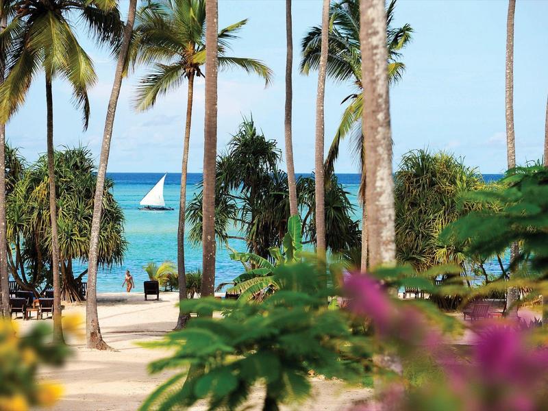 Gemütliches Restaurant mit roten Tischtüchern und Holzstühlen unter einem hohen Strohdach.