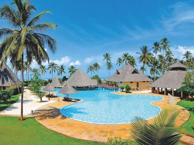 Großer Pool in tropischem Resort mit Palmen und Strohdachbungalows unter blauem Himmel.