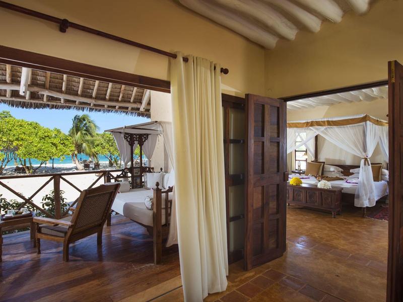 Blick von einem Zimmer mit Holzfußboden auf eine Terrasse mit Pool und Garten.