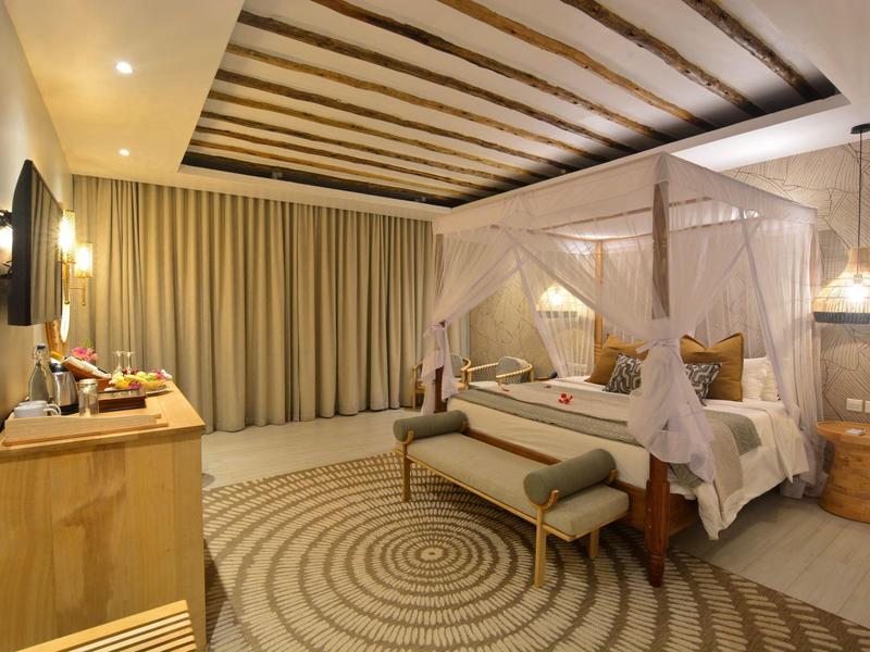 Elegantes Hotelzimmer mit Himmelbett, gemütlicher Sitzbank und flachem Fernseher.