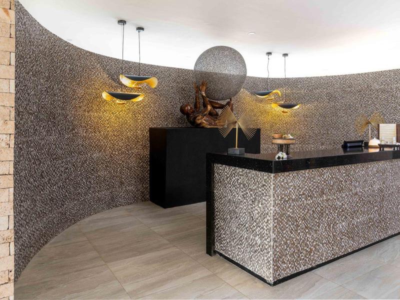 Moderne Rezeption mit geschwungenem Tresen, warmen gelben Leuchten und Steinwanddekor.