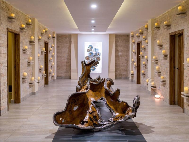 Moderner Flur mit Holzskulptur, Wänden aus Stein und zahlreichen Wandkerzen.