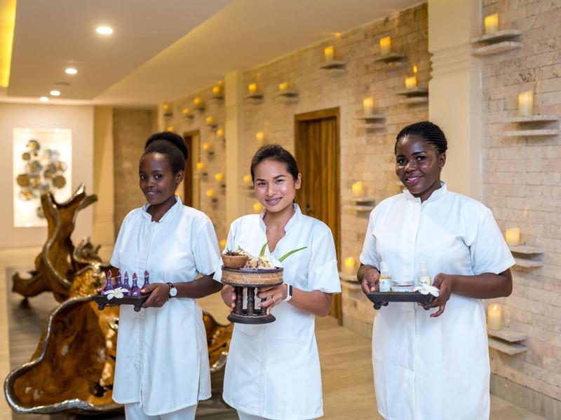 Drei lächelnde Krankenschwestern in weißer Uniform tragen Tabletts mit medizinischen Utensilien in hellen Raum.