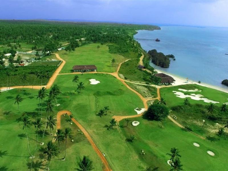 Landschaft mit grünem Gelände, Bäumen, Wegen und Küste mit Meer und felsiger Bucht.