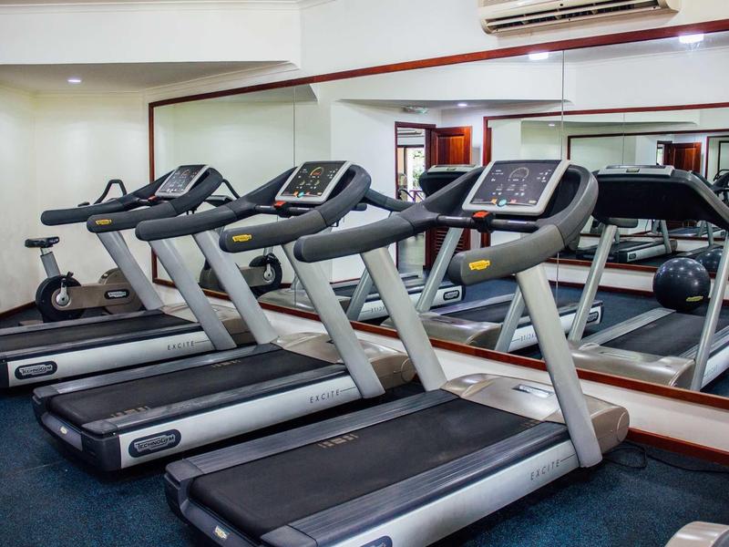 Drei moderne Laufbänder mit Displays stehen in einem hellen Fitnessraum vor einem großen Wandspiegel.