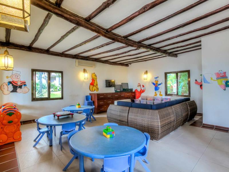 Heller Raum mit Holzbalkendecke, farbenfrohen Kindermöbeln und dekorativen Wandmalereien.