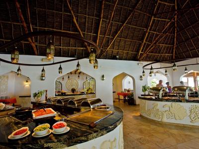 Innenbereich einer Lodge mit rustikalem Dach, Barbereich und Speisetischen mit Snacks.