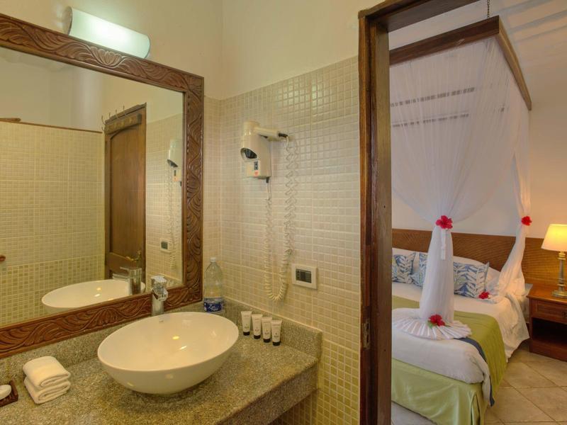 Modernes Hotelzimmer mit Bad, Waschbecken und gemütlichem Bett mit Dekoration.