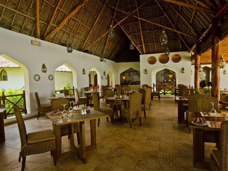 Geräumiges Restaurant mit Strohdach, Holztischen und Stühlen, eingerichtet für Gäste.