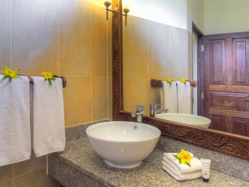 Modernes Badezimmer mit rundem Waschbecken, Handtüchern und dekorativen gelben Blumen.