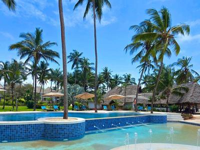 Tropical pool with palm trees and white sandy beach view at a resort