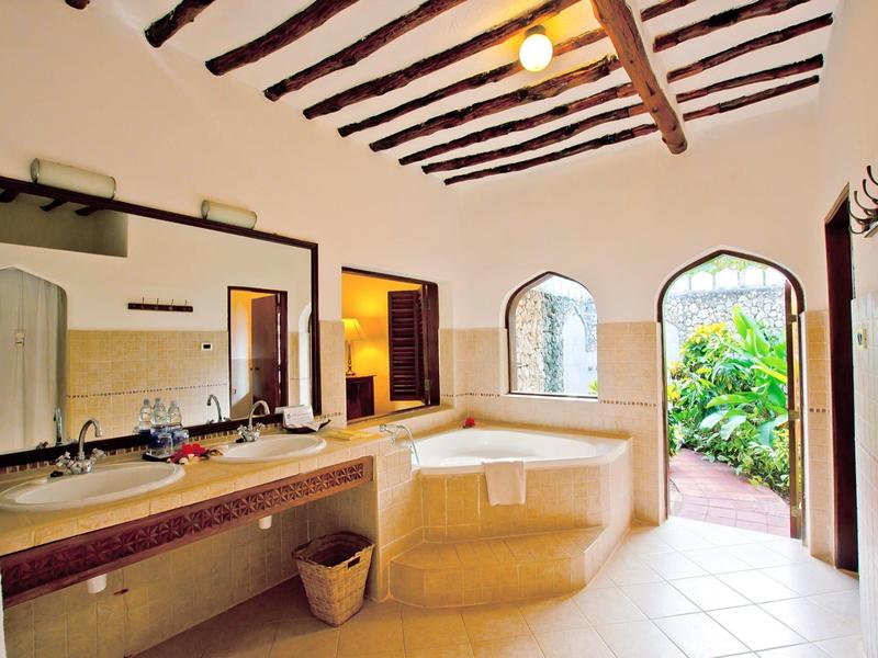 Helle Badezimmerecke mit Badewanne, zwei Fenstern und Blick in den Garten