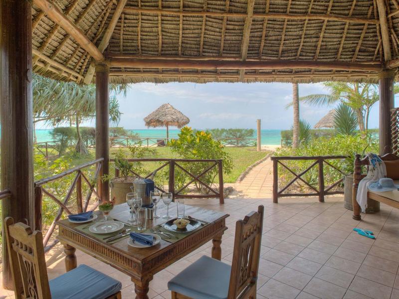 Überdachte Terrasse mit Holzmöbeln und Blick auf Strand und Meer