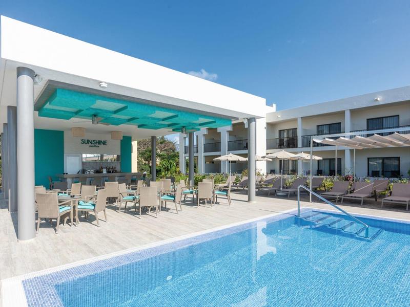 Moderner Außenbereich mit blauem Pool, weißen Sonnenschirmen und Sitzplätzen unter Pavillon.