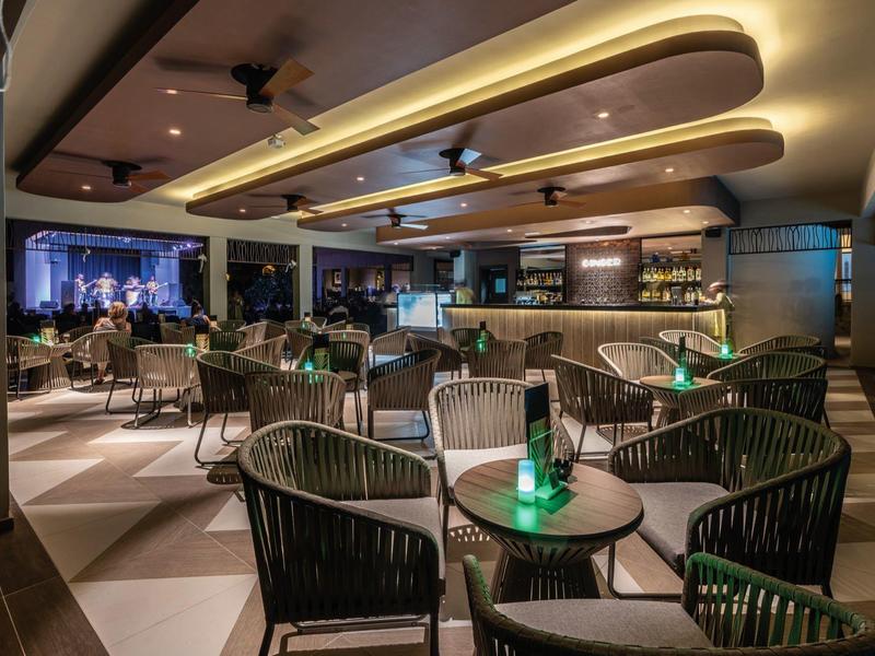 Moderner, eleganter Innenraum mit runden Tischen, dunklen Stühlen und warmem Deckenlicht.