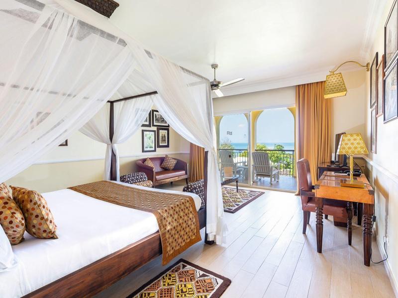 Helles, modernes Schlafzimmer mit Himmelbett, Bogenfenstern, Holzmöbeln und Zugang zu Balkon.