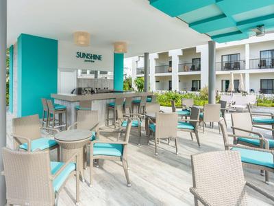 Moderner Hotelpoolbereich mit Bar, Sitzmöglichkeiten und blau-weißer Farbgestaltung.