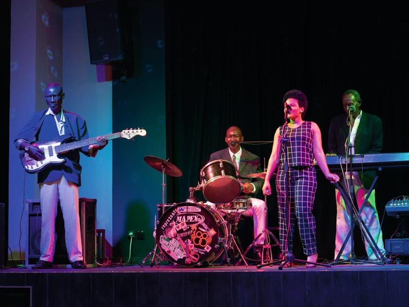 Vierköpfige Band spielt auf Bühne mit Gitarre, Schlagzeug, Keyboard und Gesang in buntem Licht.