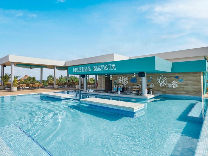 Moderner Außenpool mit Swim-up-Bar, türkisfarbenem Wasser und blauen Himmel.