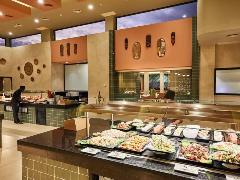 Buffetbereich mit verschiedenen Salaten in Teller, warmes Licht und moderne Dekoration.