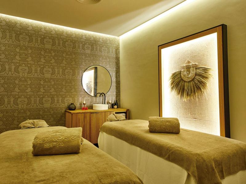 Ein ruhiger Wellnessraum mit zwei Massageliegen, warmen Beige- und Brauntönen und sanfter Beleuchtung.