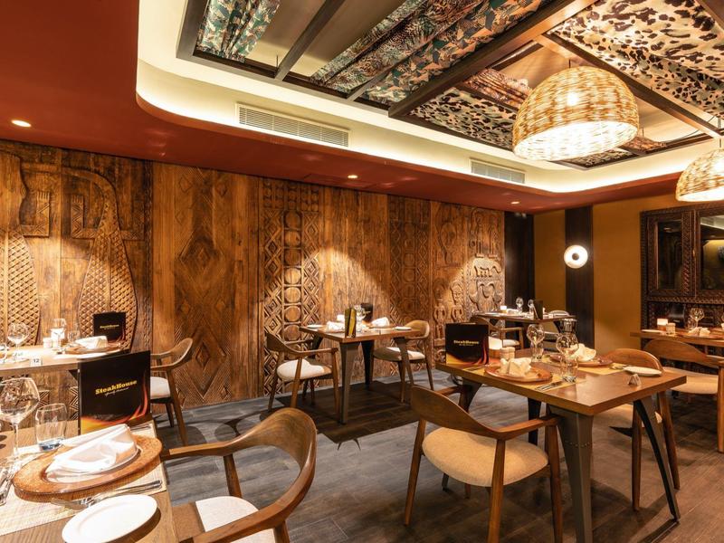 Elegantes Restaurant mit Holzwänden, Teppichboden und modernen Holzstühlen.