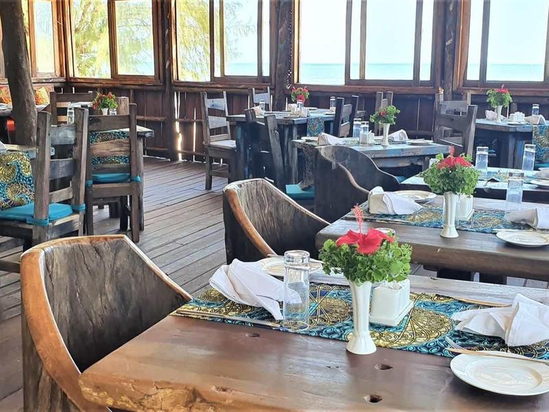 Ein rustikales Restaurant mit Holztischen, Stühlen, gedeckten Tischen und Blumenarrangements.