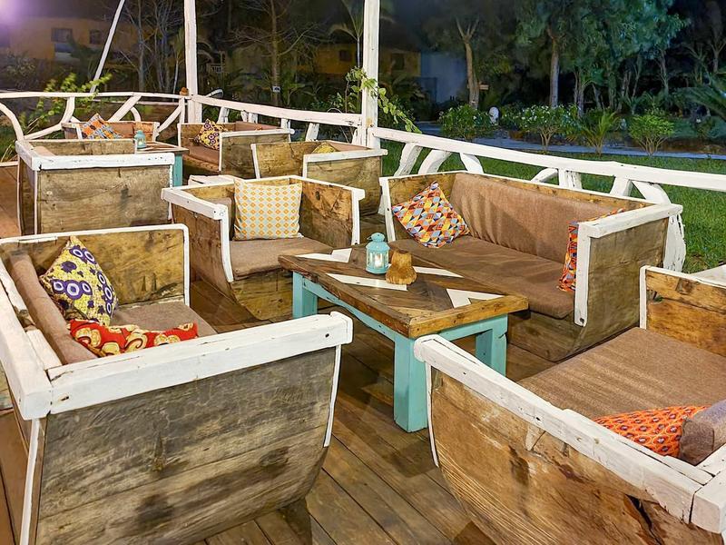 Gemütliche Außenlounge mit Holzmöbeln, bunt gemusterten Kissen und Tisch bei Nacht.