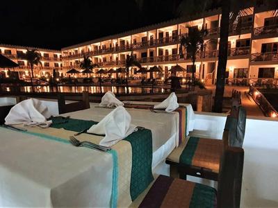 Abendterrasse mit gedecktem Tisch und beleuchtetem Hotelgebäude im Hintergrund.